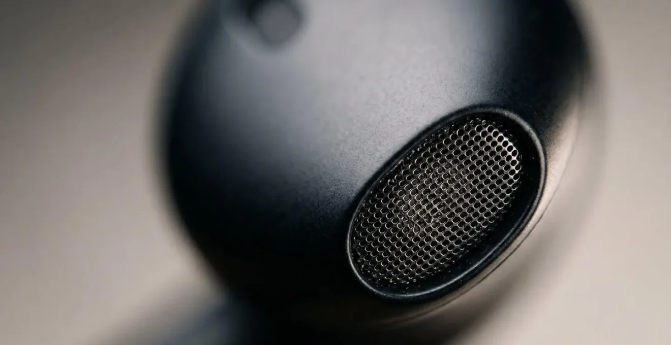 Extreme close-up macro view of earbud external microphone grille showing texture and vulnerability to blockage