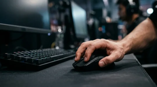 Professional esports player's hand on gaming mouse during intense competitive FPS match with motion blur emphasizing speed